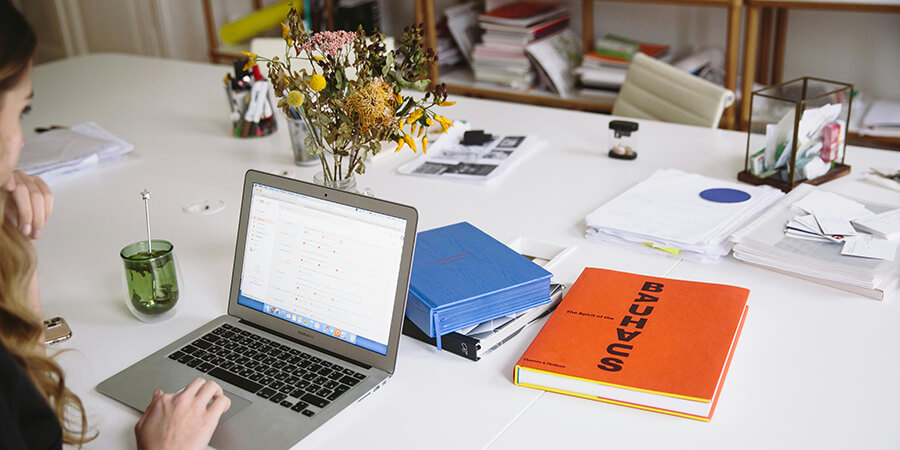 Person working on a desk witha laptop with a Bauhaus book.