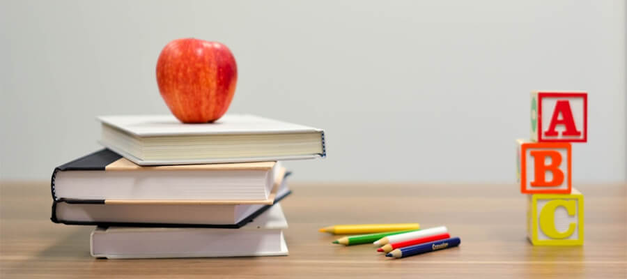 Classroom objects - books, apple, pencils and ABC blocks.