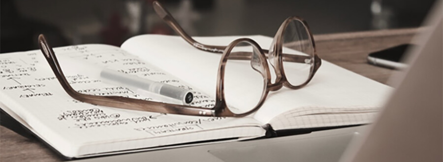 Glasses and pen on an open notebook.