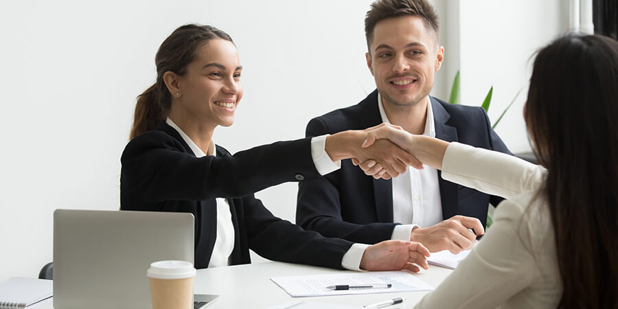 Shaking hands over a table in a business setting.