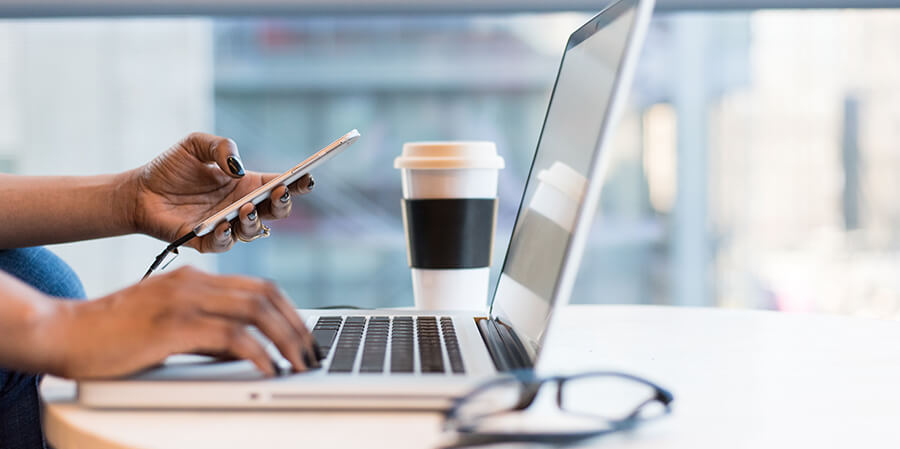 Laptop, coffee, phone close up.