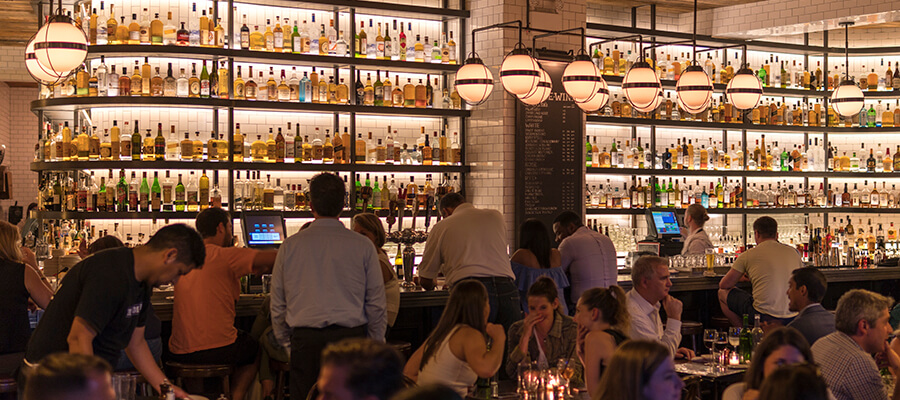 Busy restaurant and bar with many bottles.