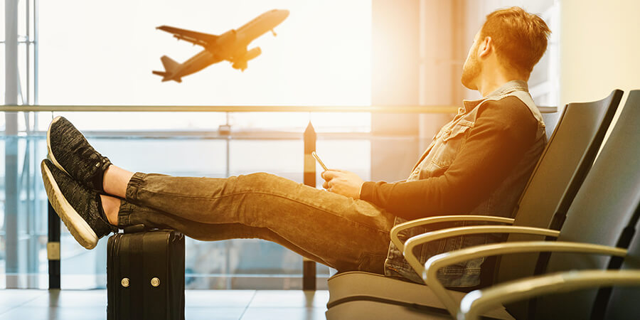 Man watching a plane take off from an airport waiting area.