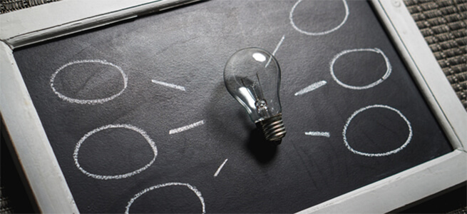 Lightbulb on a blackboard with spaces for ideas.