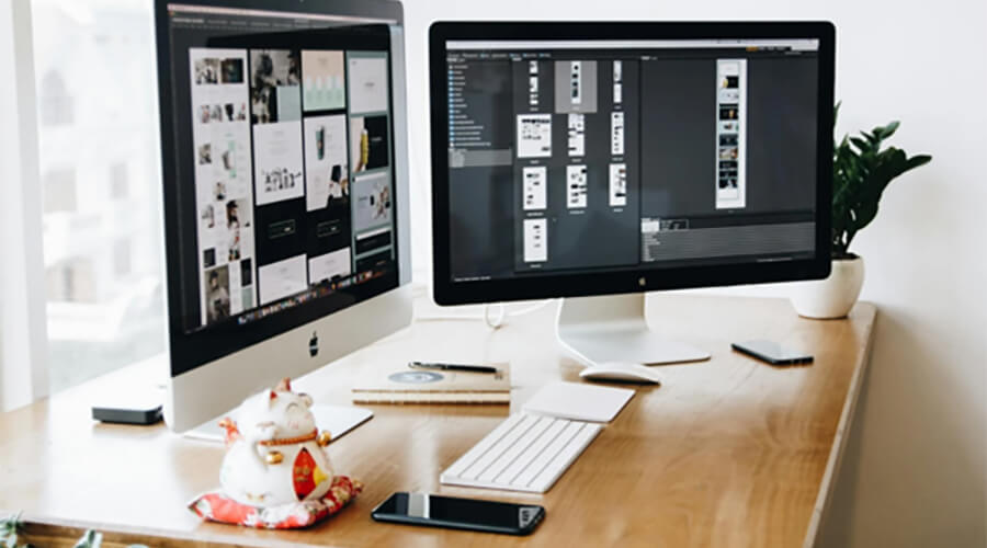 Computer with two screens on a desk.