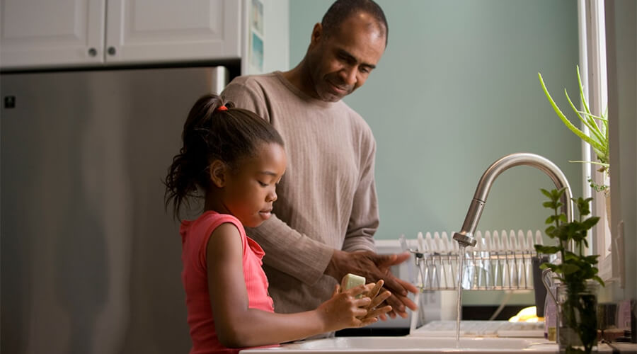 Father and daughter using the kitchen sink.