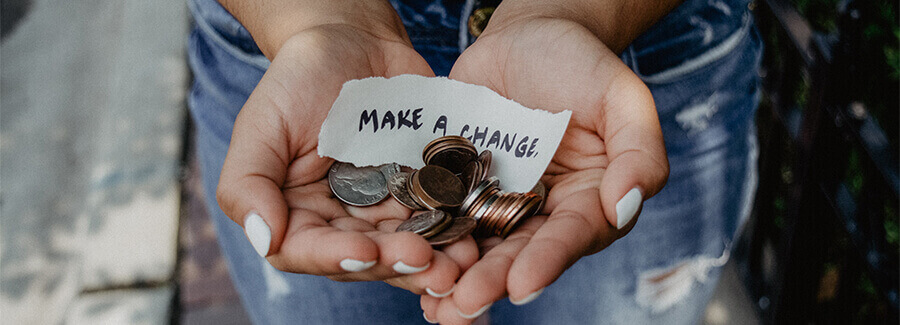 Woman's hands holding loose change with the caption - 'Make a Change'