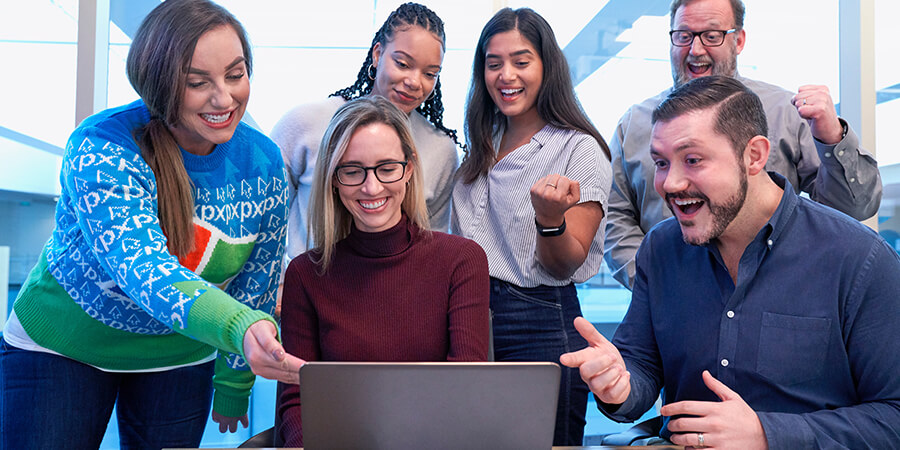 A group of happy people looking at a laptop