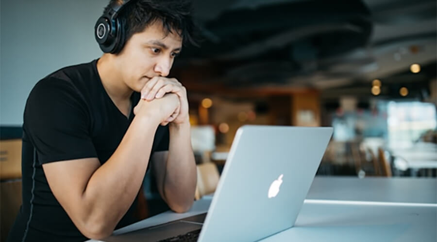 Person with headphones looking at a laptop screen.