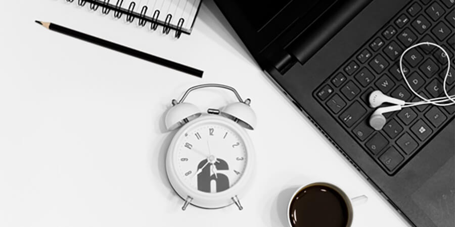 Laptop, headphones, clock, coffee, notepad and pencil.  All objects are either black or white.