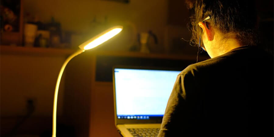 Working on a laptop with a desk lamp.