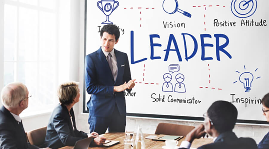 Key leader attributes on a whiteboard with people wearing suits.