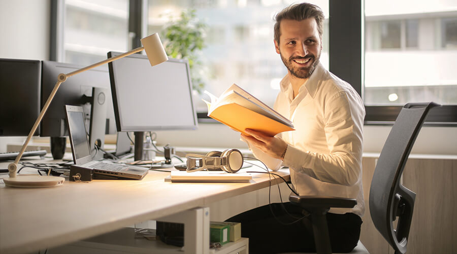 A person sitting at a desk holding a book.