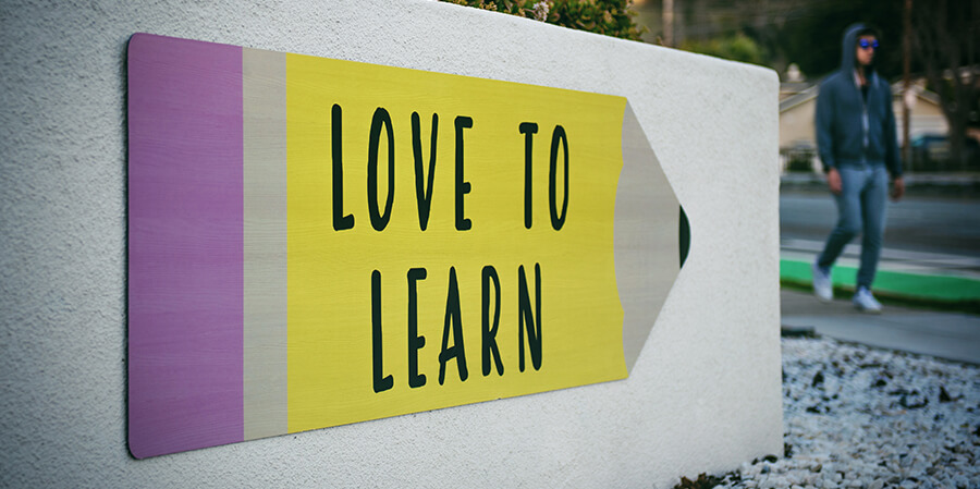 Sign with text 'love to learn' pointing at a person.