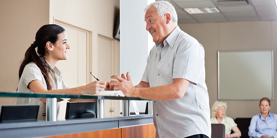 Medical admin assistant helping a patient in a waiting room.