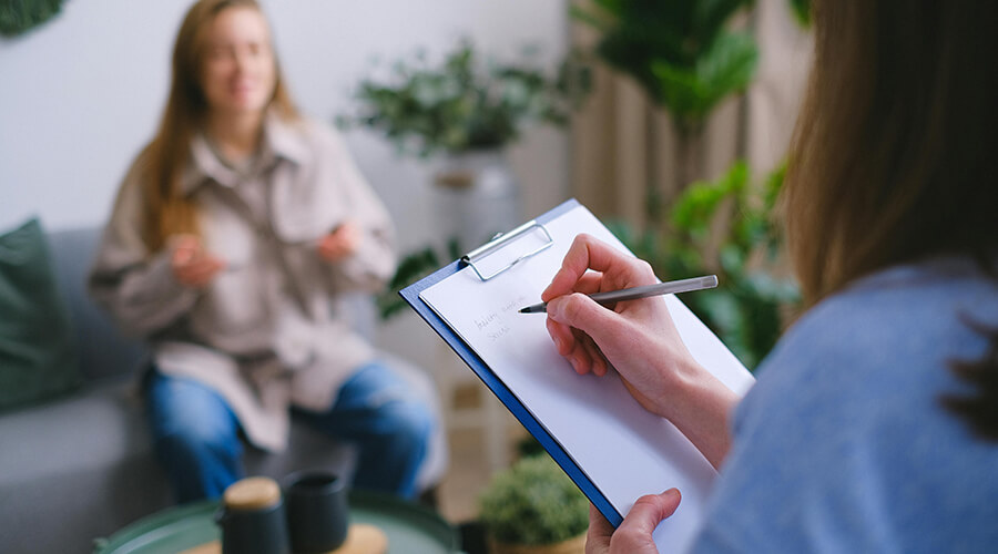 Counselor taking notes while talking to a client.