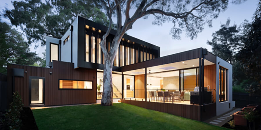 Outside a modern house with brightly lit dining room.