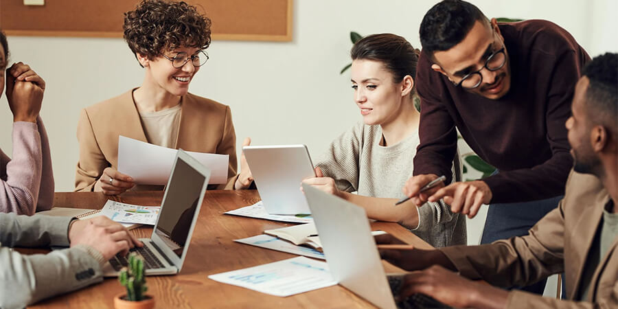 Group of people working around a table on laptops.