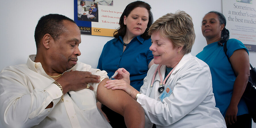 Nurse giving an injection while student nurses watch.