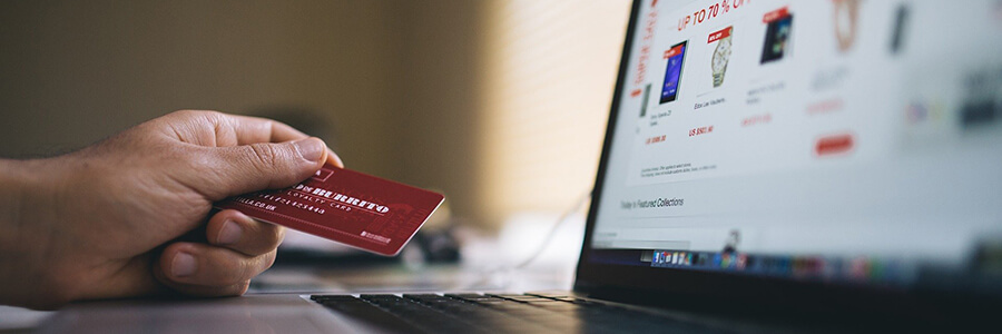 Male hand holding a credit card over a laptop.  Online payments.