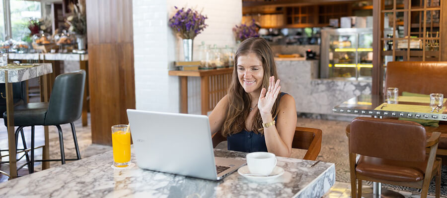 Student waving to friends online.