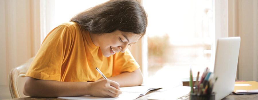 Student with a yellow tee-shirt studies online.