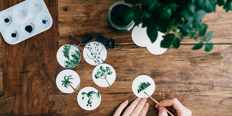 Creative person paiting plants onto white disks.