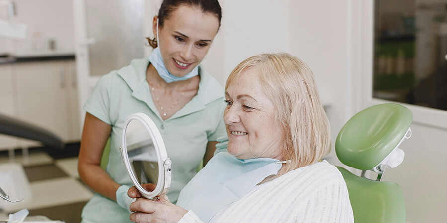 Dental paitent admiring her teeth in a mirror.