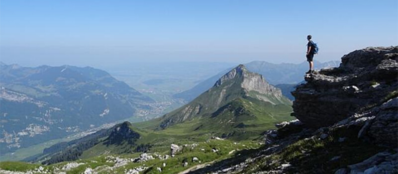 A man on a summit overlooking the land below.