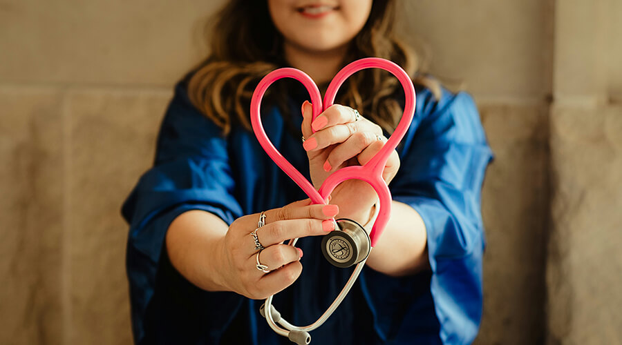 Nurse holding a pink stethoscope shaped like a heart.