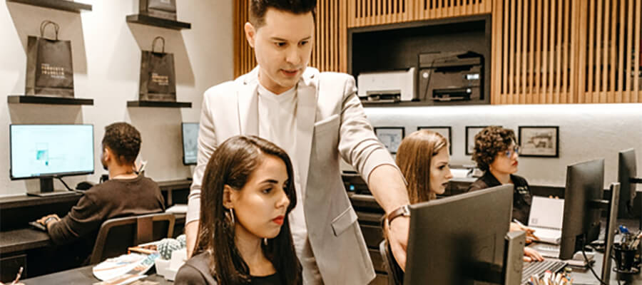 Man pointing at a woman's computer screen.