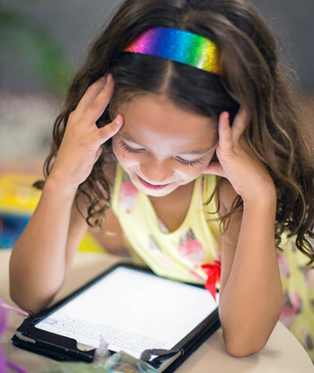 Girl child looking at a tablet.