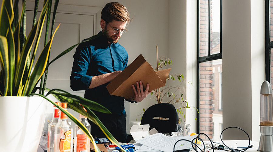 A person standing in a messy office holding a folder in his hands.