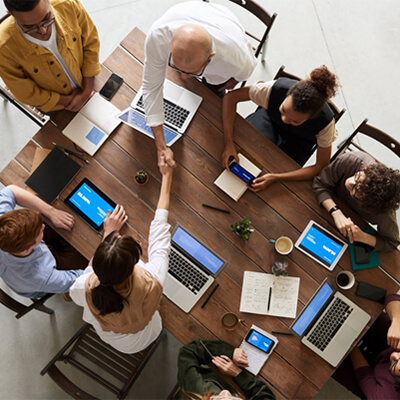 A group of professionals with laptops sitting around a table.