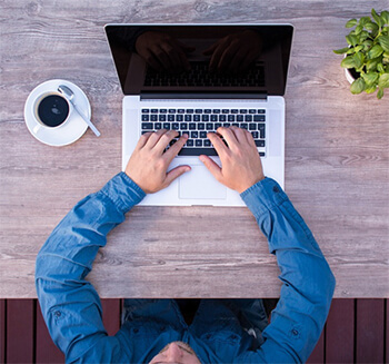 Man's hands typing on laptop.