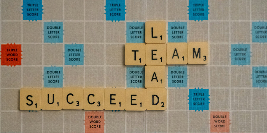 LEAD, TEAM and SUCCEED spelt out on a Scrabble board.