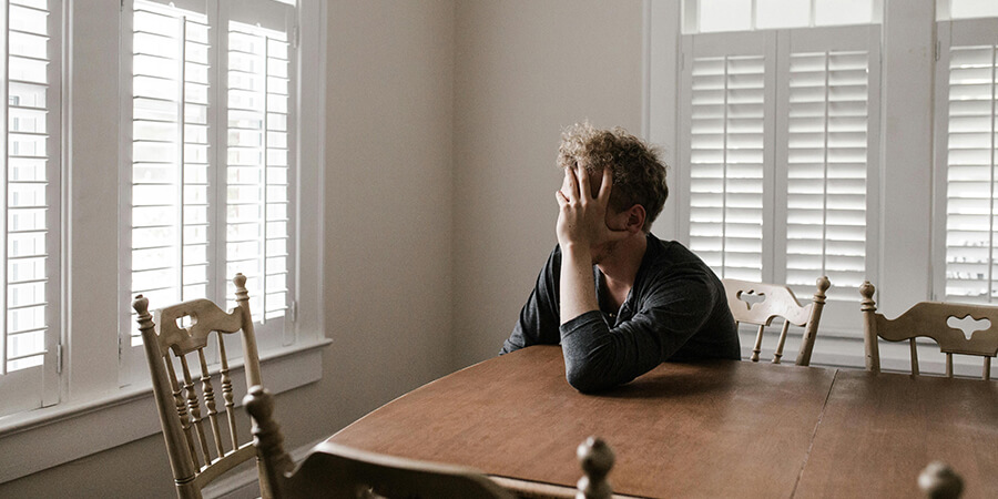 Man sitting at a wooden table looking out of a large window.