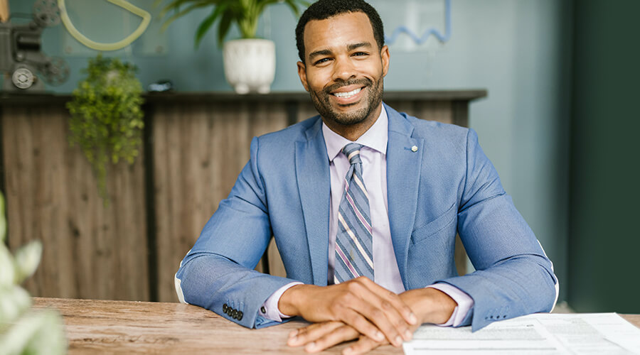 Smiling man in a suit sitting at a table.