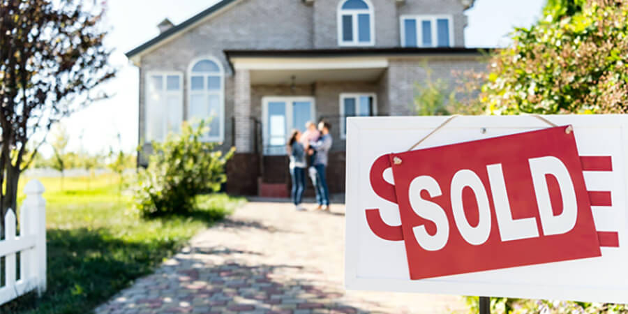 House with young family and 'Sold' sign.