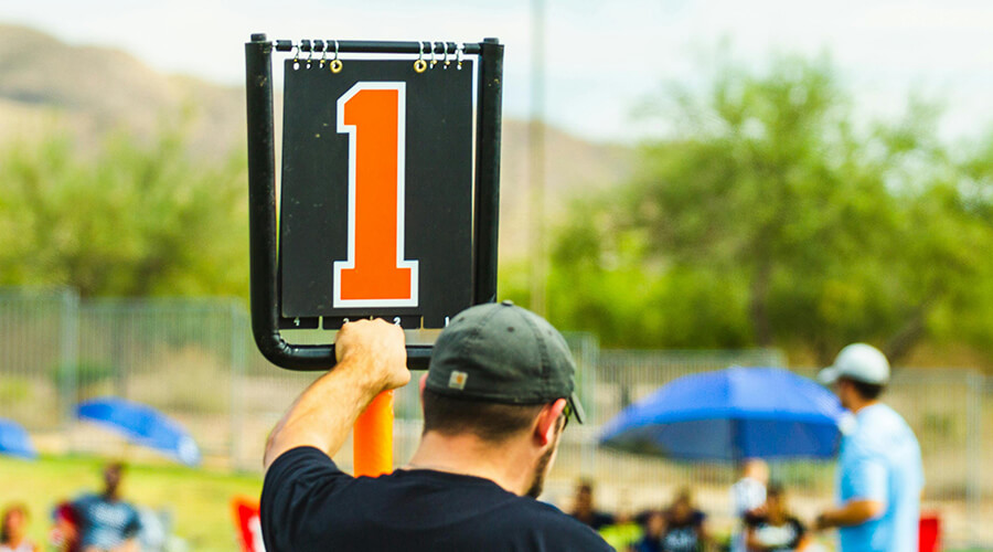 Sports coach holding up an orange number one.