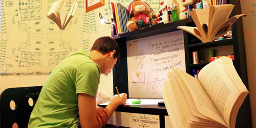 Studnet working at a desk with books flying around.