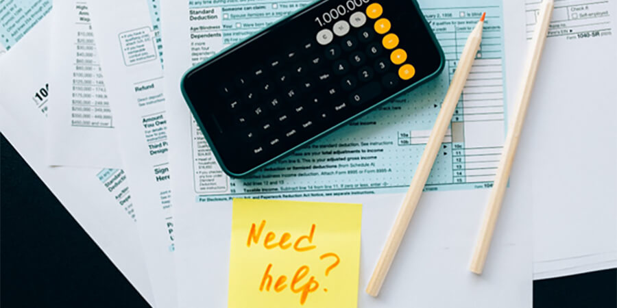 Tax forms and calculation with a PostIt reading 'Need Help?'