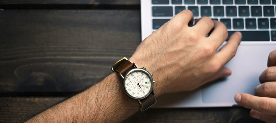 Man's arm with a Timex watch and a laptop.