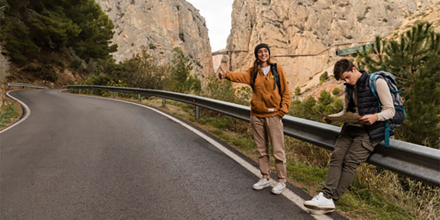 Couple hitch hiking on a highway in the mountains.