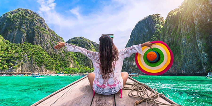 Woman with a big brightly coloured hat on a boat in Thailand.