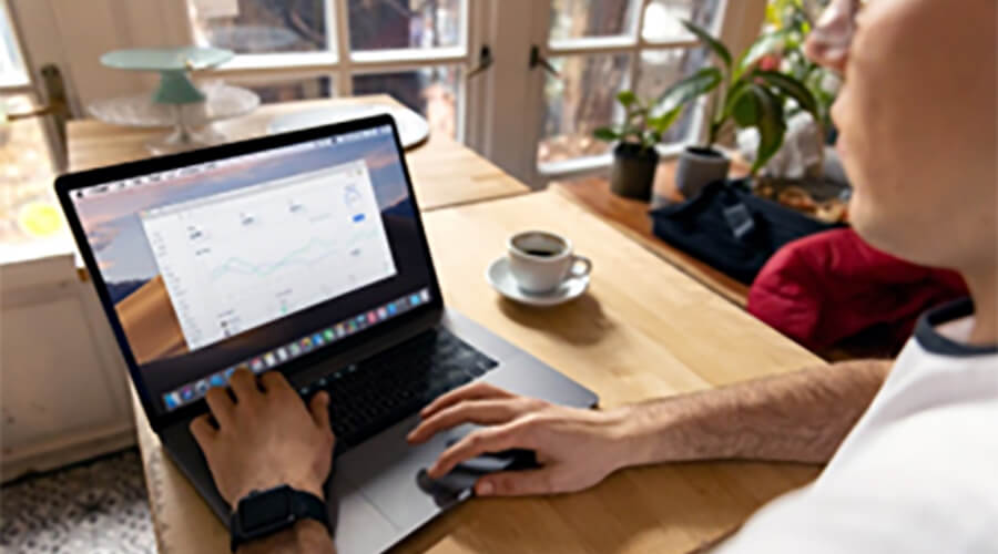 Person using a laptop on a wooden table.