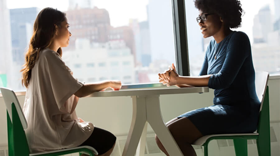 Two women talking across a round table.