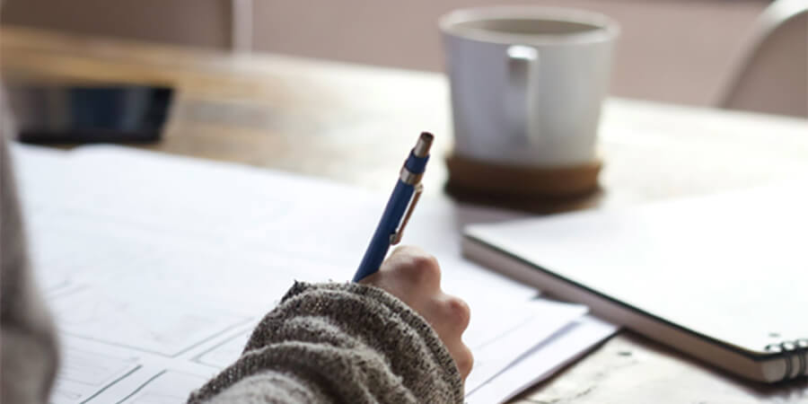 Close up of person writing with a pen and paper.